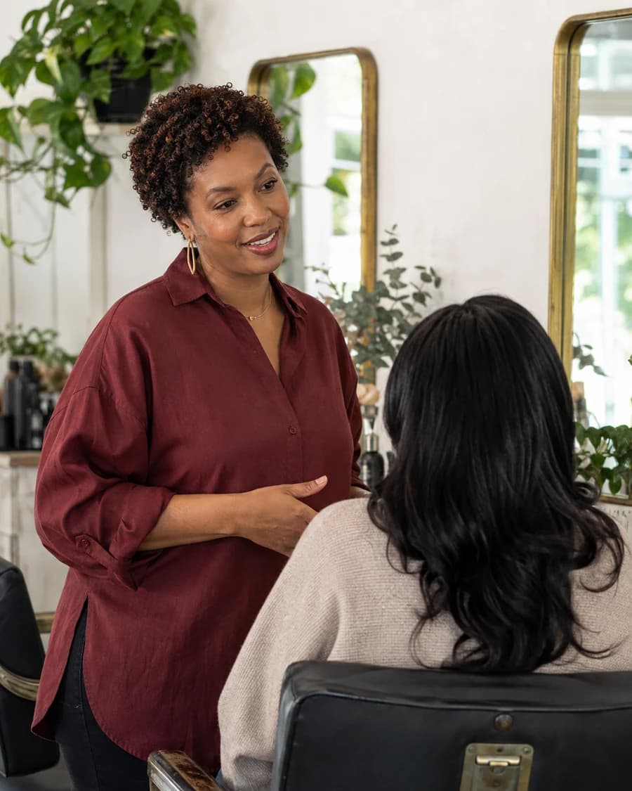 A salon owner in burgundy talking with a client