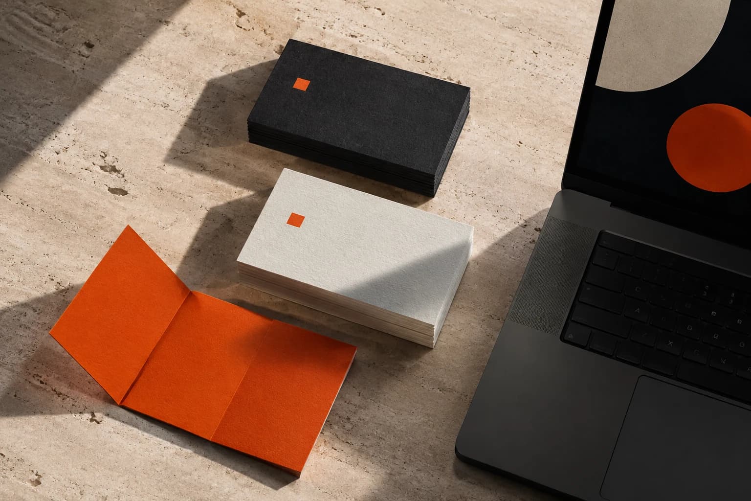 A studio composition of business cards, brand materials and a laptop